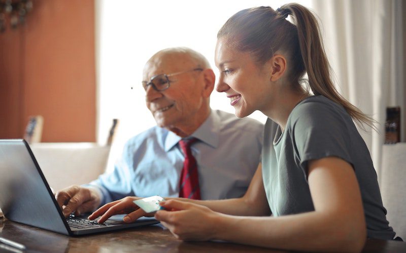 woman assisting senior with laptop