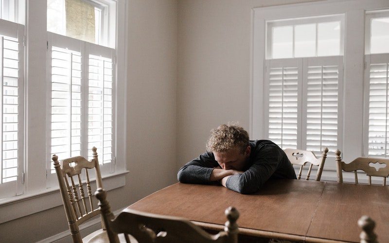 man hunched over at dining room table